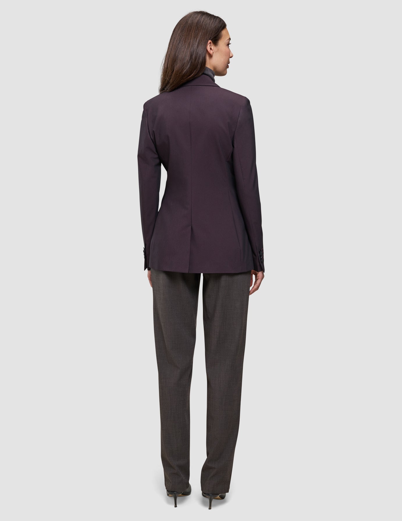 En kvinna sedd bakifrån, klädd i en mörk vinröd Women’s Avira Blazer Burgundy Berry och byxor i kolgrått.
